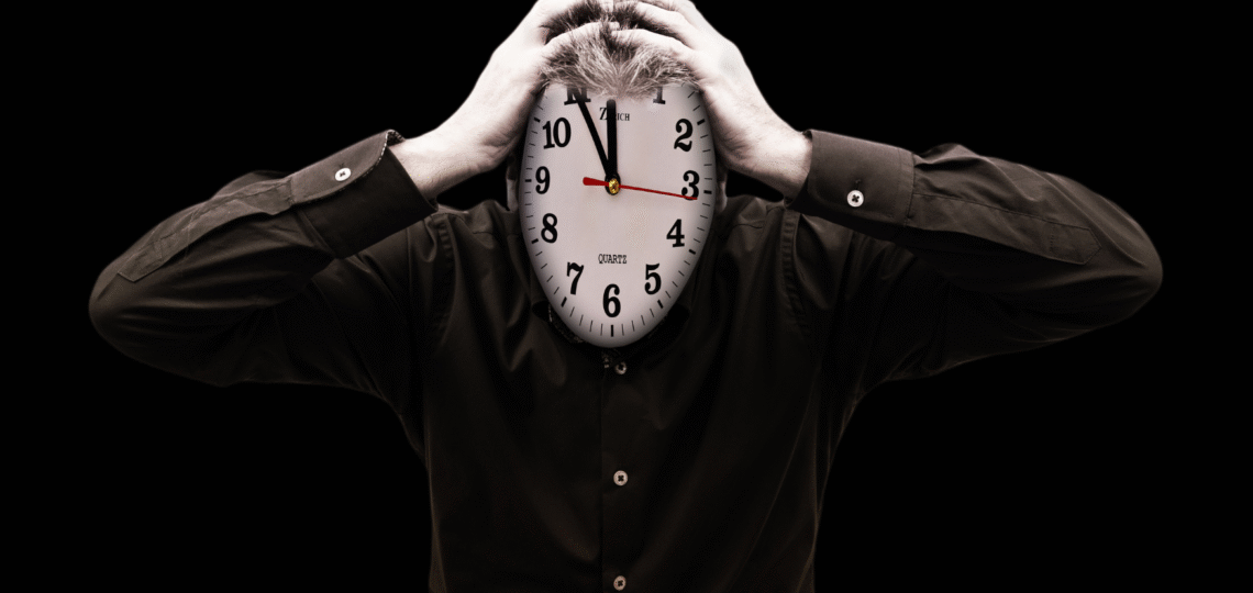 Man holding his clock head procastinating